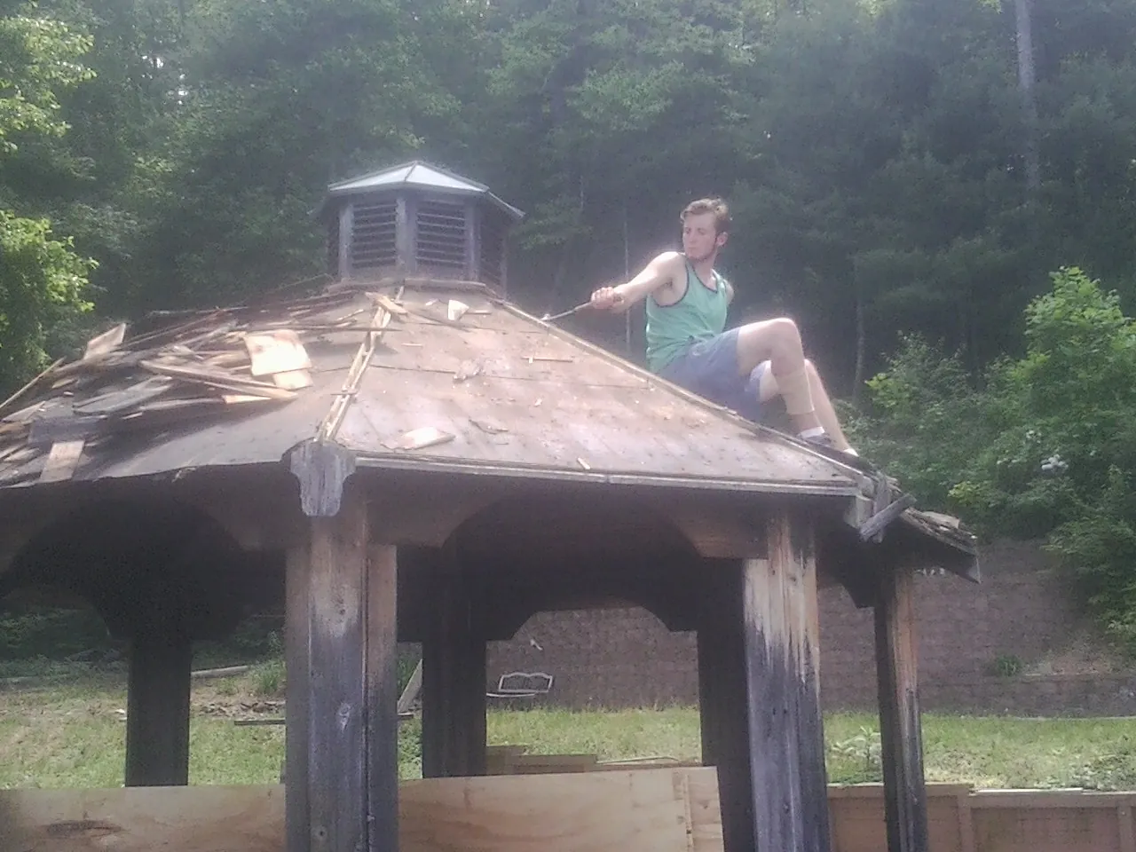 Tearing the old roof off a wooden gazebo before new shakes in Littleton